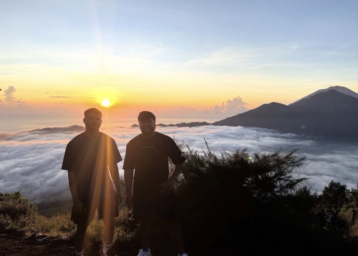 Hiker wearing a headlamp and warm jacket on a dark volcanic trail before sunrise in Bali